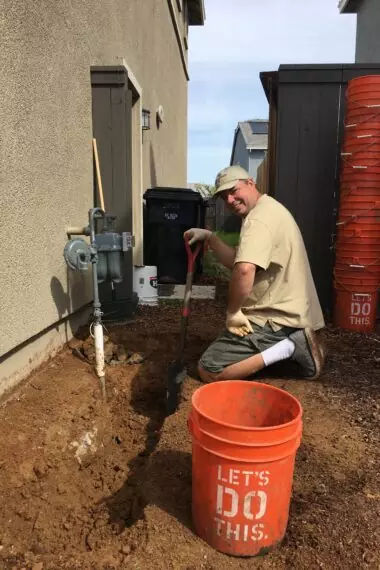 A man kneeling down next to a bucket.