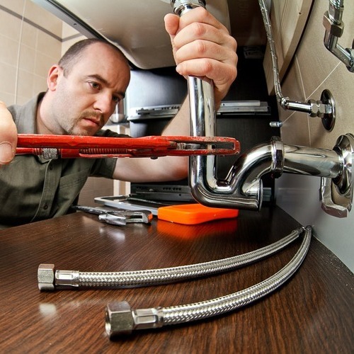 A man working on pipes in the kitchen