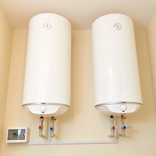 Two water heaters are connected to a wall.