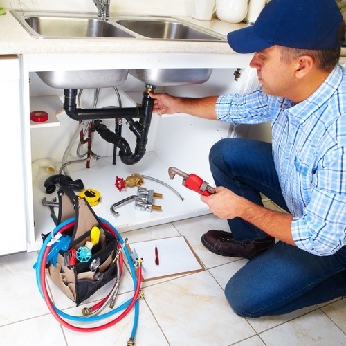 A man working on the pipes of a sink.