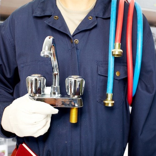 A person holding two pipes and one faucet