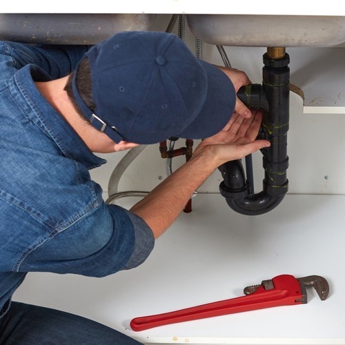 A man working on the pipes of a sink.