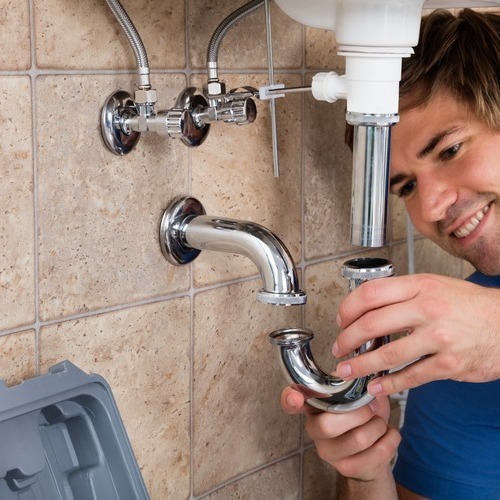 A man fixing pipes in the bathroom