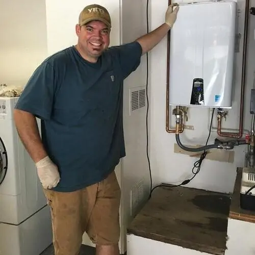 A man standing next to an electric water heater.