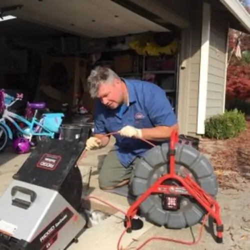 A man working on an electric cable in the driveway.