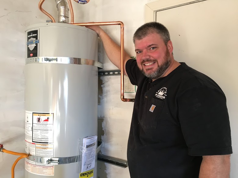 Plumber smiling next to a water heater.